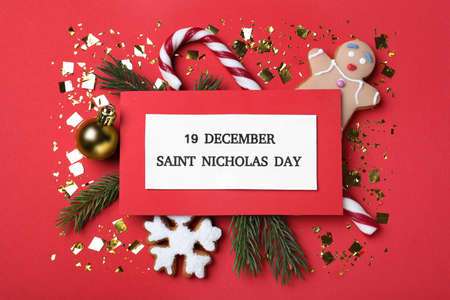 Card with text 19 December Saint Nicholas Day and festive decor on red background, flat lay