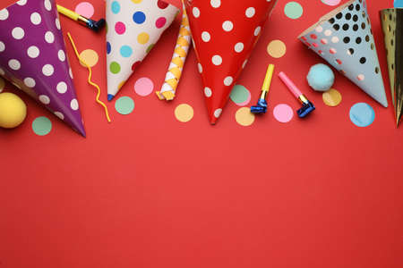 Flat lay composition with party hats and other festive items on red background. Space for textの写真素材