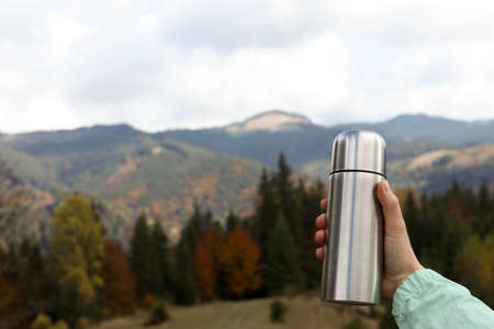 Woman holding silver flask in mountains, closeup. Space for textの写真素材