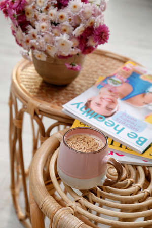 Cup of fresh coffee, magazines and beautiful bouquet on wooden stands. Good morningの写真素材