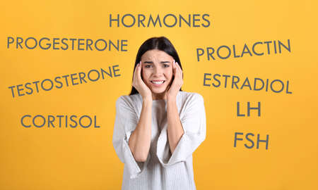 Hormones imbalance. Stressed young woman and different words on yellow backgroundの写真素材