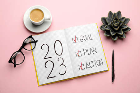 Flat lay composition of notebook with text 2023 Goal, Plan, Action on pink background. New Year aimsの写真素材