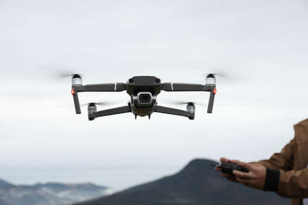 Man operating modern drone with remote control in mountains