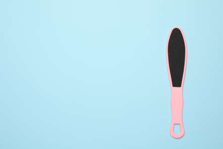 Pink foot file on light blue background, top view with space for text. Pedicure tool