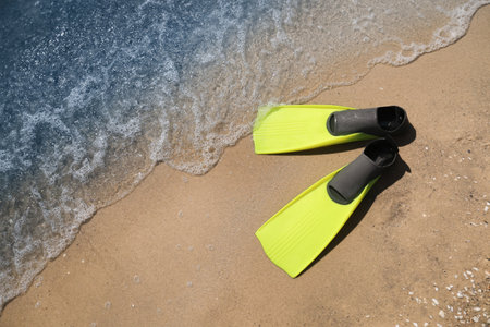 Pair of yellow flippers on sand near sea, top view. Space for textの写真素材