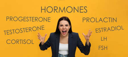 Hormones imbalance. Annoyed young woman and different words on yellow background, banner designの写真素材