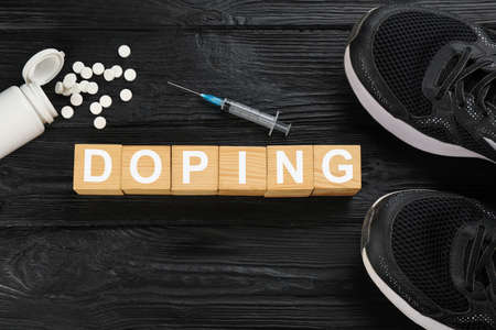 Cubes with word Doping, sport shoes and drugs on black wooden background, flat layの写真素材