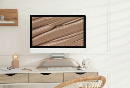 Comfortable workplace with modern computer and lamp in room. Interior design