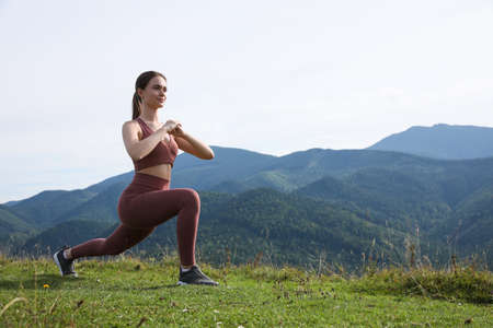 Young woman doing morning exercise in mountains, space for textの写真素材