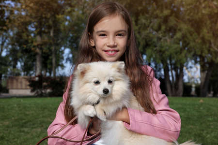 Little girl with her cute dog in park. Autumn walkの写真素材