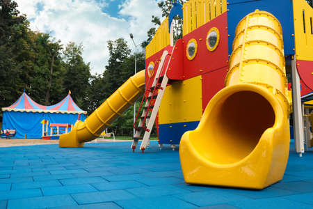 Children's playground with bright yellow slide on autumn day