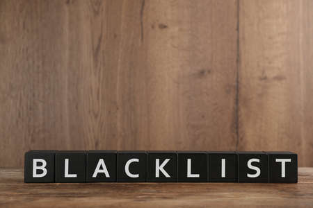 Black cubes with word Blacklist on wooden tableの写真素材