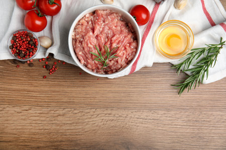 Raw chicken minced meat and ingredients on wooden table, flat lay. Space for textの写真素材