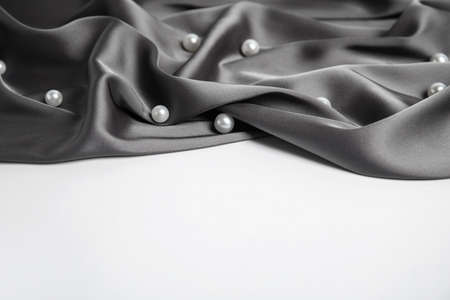 Texture of delicate black silk with pearls on white background
