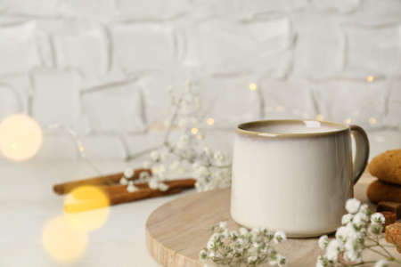 Cup of hot beverage and flowers on white wooden table, bokeh effect. Space for textの写真素材