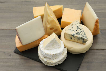 Different types of delicious cheeses on wooden tableの写真素材