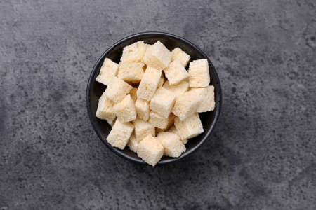 Crispy rusks in bowl on gray table, top view