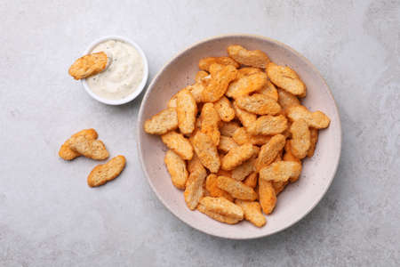 Crispy rusks and dip sauce on light table, flat lay