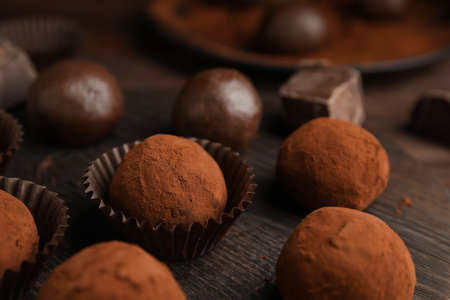 Delicious chocolate truffles powdered with cocoa on wooden board, closeupの写真素材