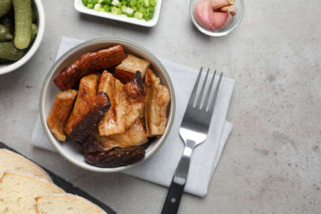 Bowl with tasty fried pork fatback slices on gray table, flat layの写真素材