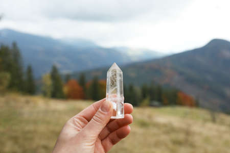 Woman holding beautiful crystal in mountains, closeupの写真素材