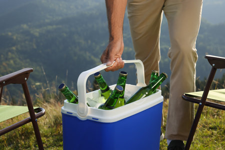 Man holding cool box with bottles of beer in nature, closeupの写真素材