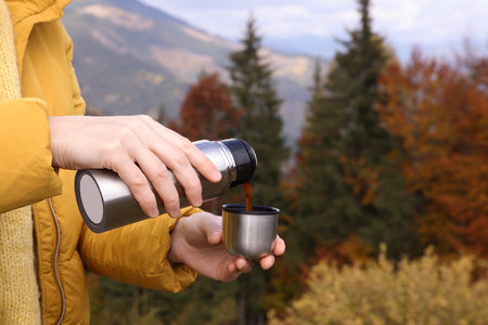 Young woman pouring instant coffee into mug in mountains, closeupの写真素材