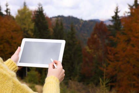 Woman drawing with graphic tablet in mountains on autumn day, closeupの写真素材