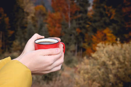Young woman with mug of hot instant coffee near forest, closeupの写真素材