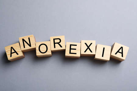 Word Anorexia made of wooden cubes with letters on light gray background, flat layの写真素材