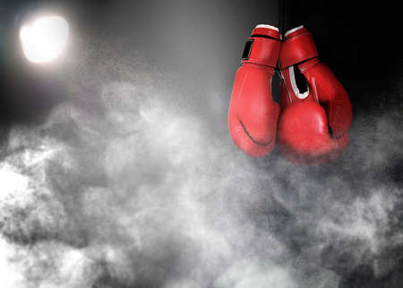 Pair of boxing gloves and white smoke illuminated by spotlight on dark backgroundの写真素材