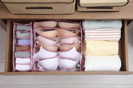 Open drawer with folded clothes and underwear indoors, top view. Vertical storageの写真素材