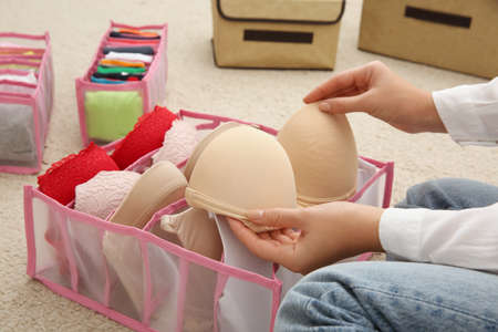 Woman folding clothes on floor, closeup. Japanese storage system