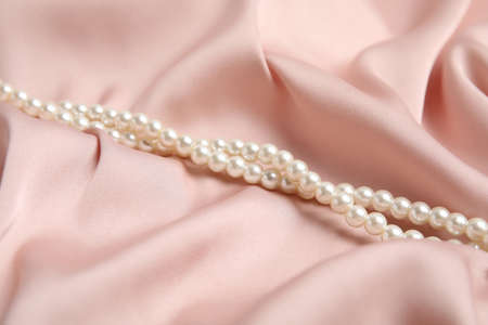 Beautiful white pearls on delicate pink silkの写真素材