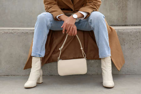 Stylish woman with trendy beige bag on stairs outdoors, closeupの写真素材