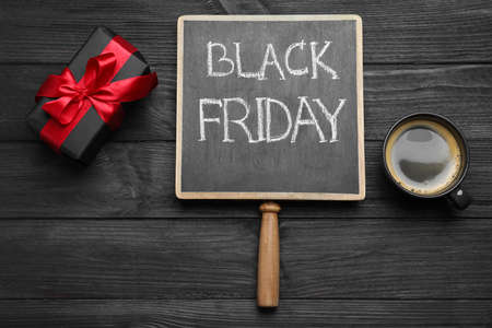 Chalkboard with words Black Friday, gift box and cup of coffee on wooden table, flat layの写真素材