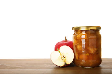 Tasty apple jam in glass jar and fresh fruits on wooden table against white background, space for textの写真素材