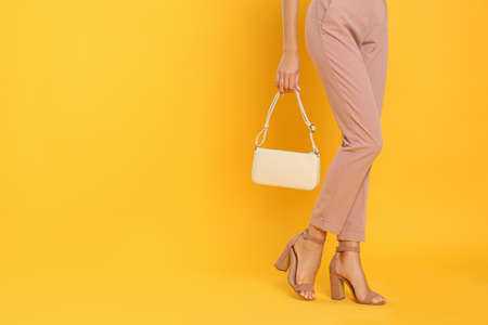 Woman with stylish bag on yellow background, closeup. Space for textの写真素材