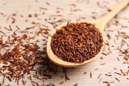 Spoon with dry rooibos leaves on wooden table, closeupの写真素材