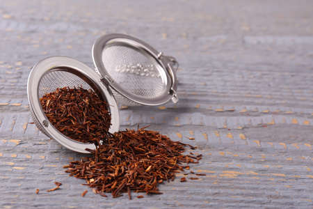 Infuser with dry rooibos leaves on gray wooden table, space for textの写真素材