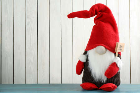 Cute Christmas gnome on turquoise table against white wooden background. Space for textの写真素材