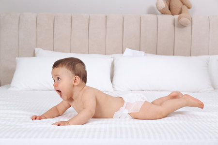 Cute baby in dry soft diaper on white bed at homeの写真素材