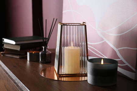 Burning scented candles on wooden table indoors