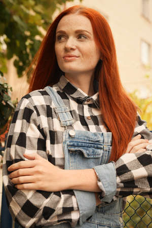 Portrait of beautiful young woman with red hair near fence outdoors
