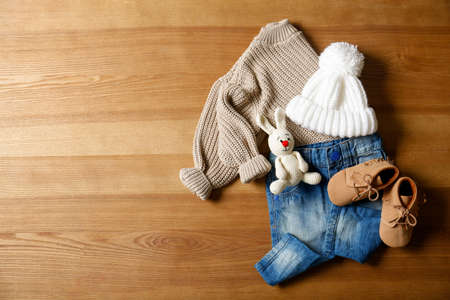 Children's shoes, clothes, toy and pacifier on wooden table, flat lay. Space for textの写真素材