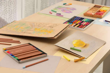 Artist's workplace with drawings, soft pastels and color pencils on tableの写真素材