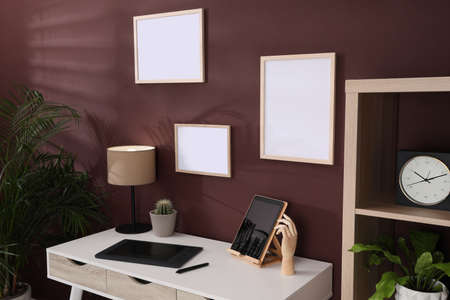 Empty frames hanging on brown wall indoors. Mockup for design