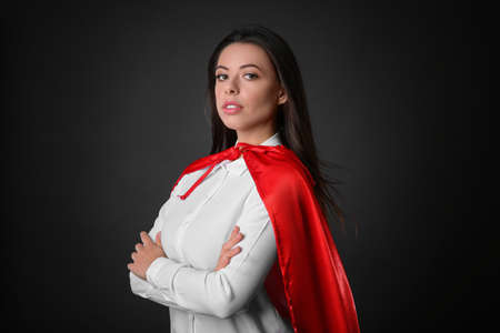 Confident businesswoman wearing superhero cape on gray backgroundの写真素材