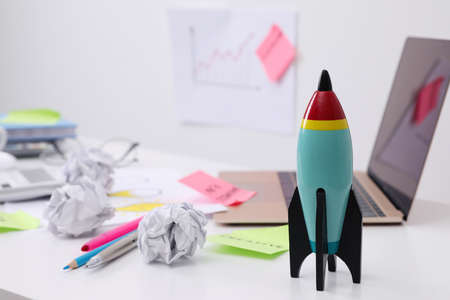 Toy rocket, laptop and crumpled paper on messy table indoors, space for text. Startup conceptの写真素材