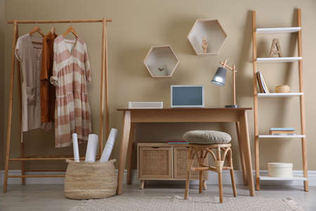 Comfortable wooden stool near table with laptop indoors. Interior designの写真素材